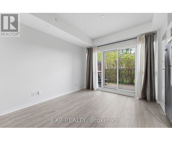 A spacious room with a sliding glass door leading to a balcony.