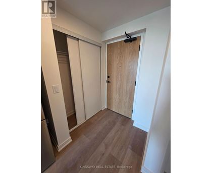 A kitchen with a refrigerator and a wooden door.