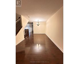 A long hallway with wood floors and a chandelier.