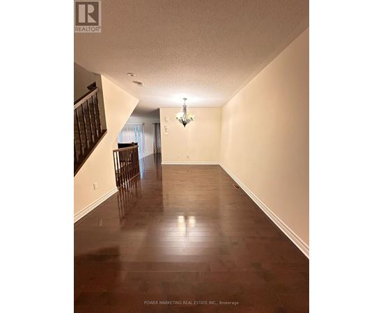 A long hallway with wood floors and a chandelier.
