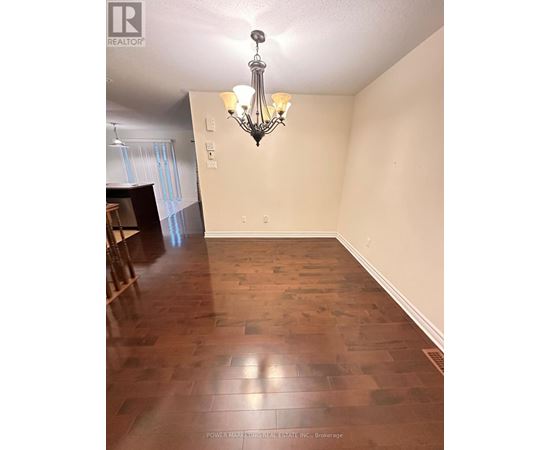 A room with wooden flooring and a chandelier hanging from the ceiling.