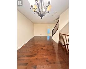 A long hallway with wood floors and a chandelier.