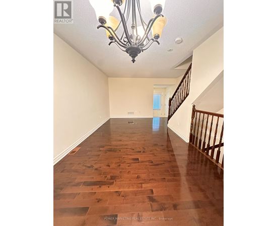 A long hallway with wood floors and a chandelier.