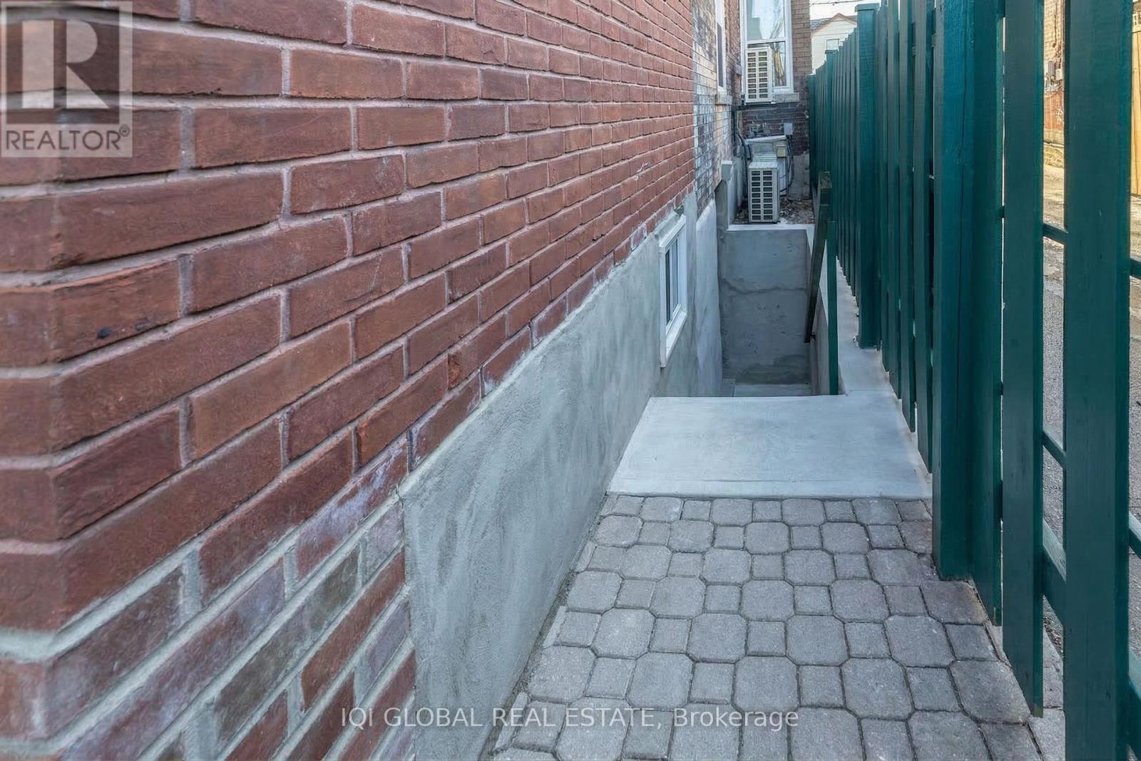 A brick wall with a green fence on the right side.