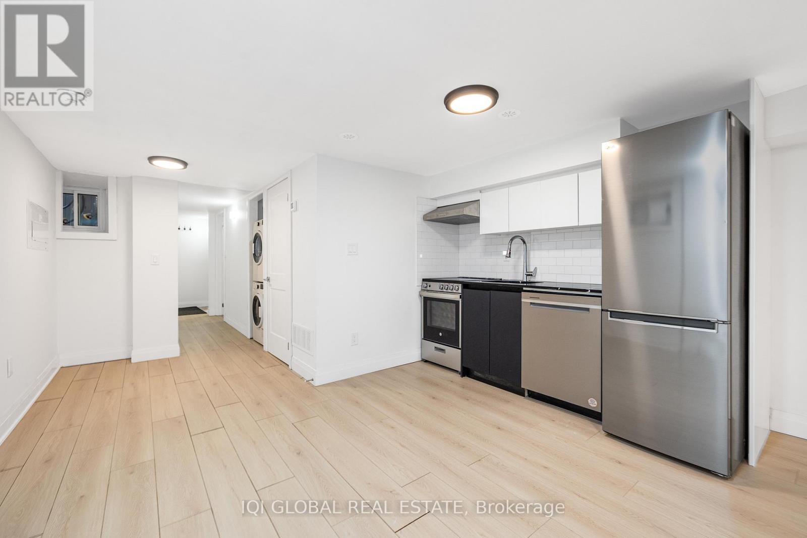 A kitchen with a refrigerator, oven, and sink.