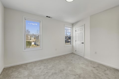A room with a carpeted floor and a window showing a view of a building.