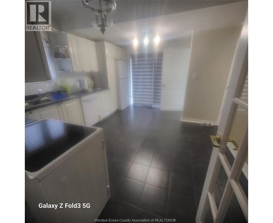 A kitchen with black tile flooring and white walls.