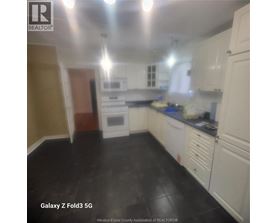 A kitchen with white cabinets and black flooring.