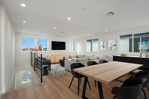 A modern living room with a wooden dining table and black chairs.