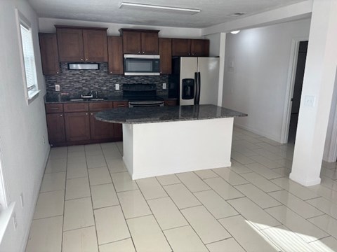 A kitchen with a black countertop and white appliances.