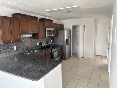 A kitchen with granite countertops and white tile flooring.