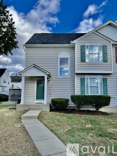 A house with a grey siding and a green door is for sale.