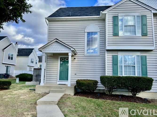 A house with a green door and white siding is for sale.