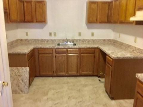 A kitchen with brown cabinets and a marble countertop.