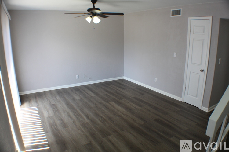 A room with a ceiling fan and wood flooring.
