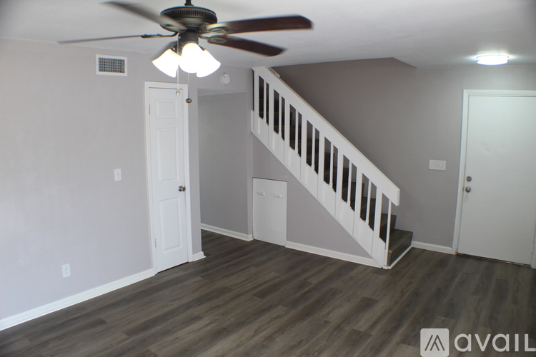 A room with a ceiling fan and wooden flooring.