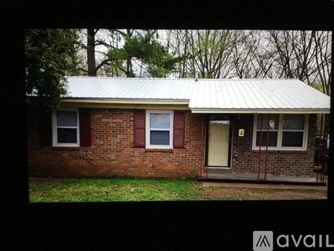 A house with a metal roof and brick walls is for sale.