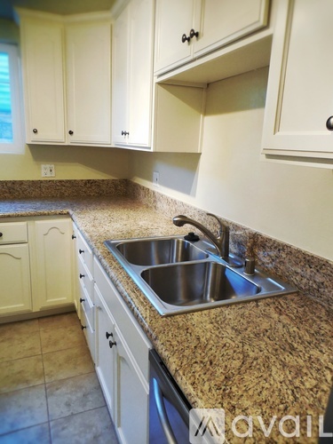A kitchen with granite countertops and white cabinets.