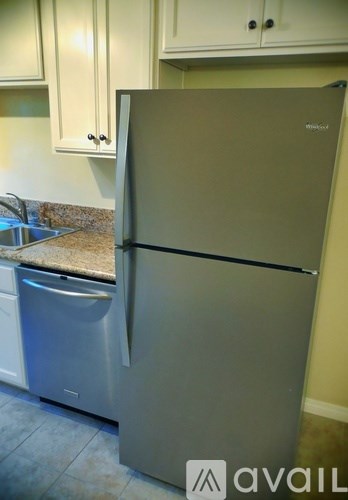 A silver refrigerator in a kitchen with a stainless steel dishwasher.