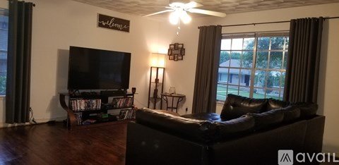 A living room with a black couch and a television.