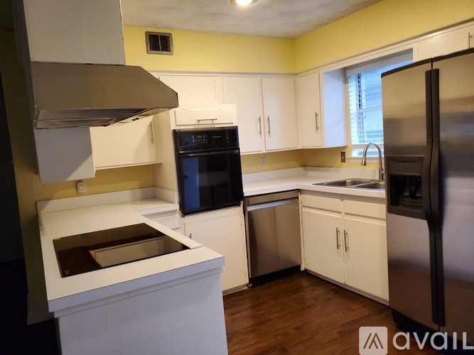 A kitchen with white cabinets and a black refrigerator.
