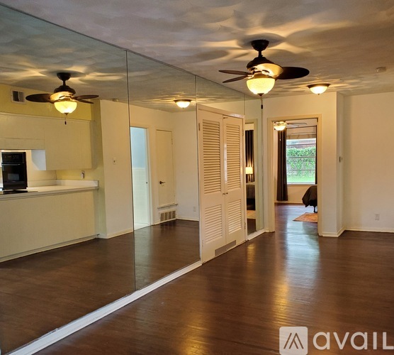 A spacious room with a ceiling fan and wooden flooring.