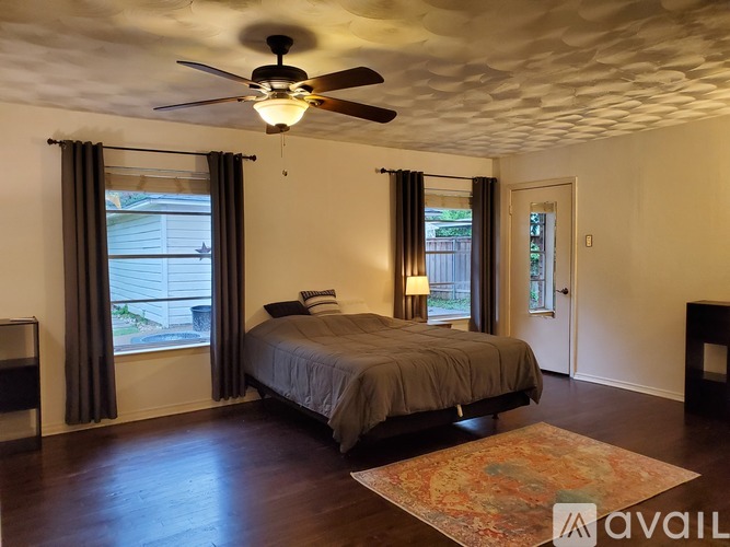 A bedroom with a bed, a ceiling fan, and a window with curtains.