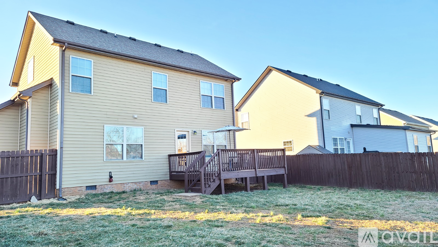 A house with a wooden fence and a deck in front.