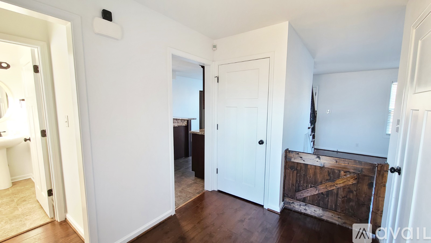 A white door is open to a room with a wooden floor.
