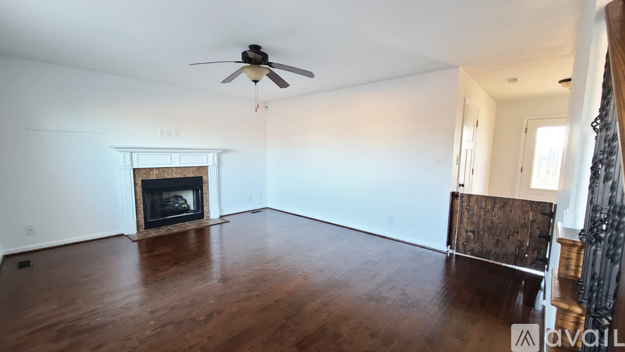 A living room with a fireplace and a fan.