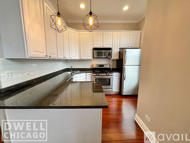 A kitchen with white cabinets and a black countertop.