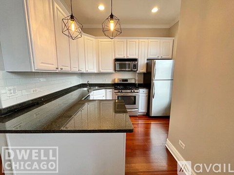 A kitchen with white cabinets and a black countertop.