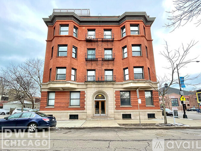 A red brick building with a black car parked in front.