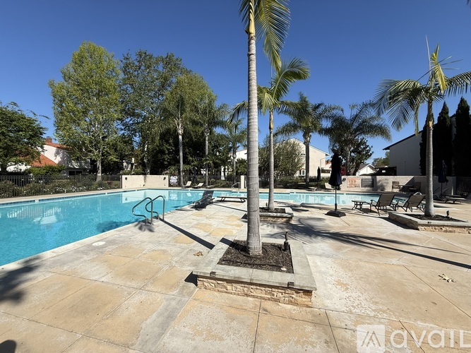 A pool surrounded by palm trees and a tall tree in the middle.