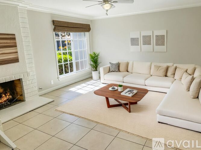 A living room with a white couch, a fireplace, and a coffee table.