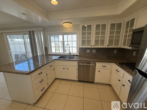 A kitchen with white cabinets and a granite countertop.