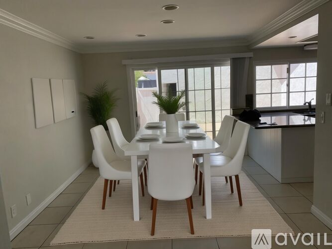A dining room with a white table and chairs.
