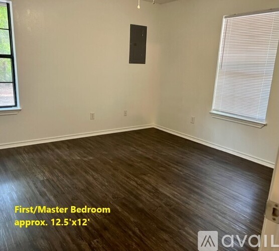 A spacious first/master bedroom with hardwood flooring and a window.