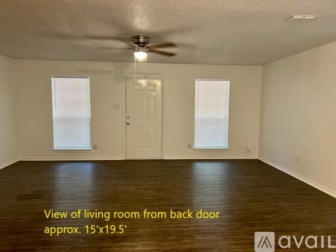 A living room with a ceiling fan and two windows.