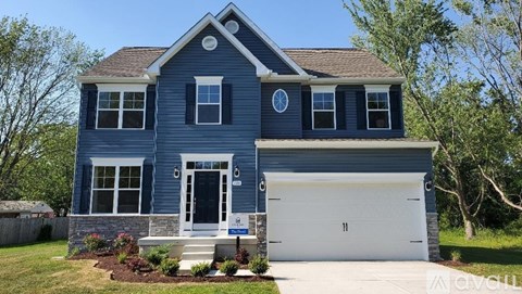 A blue house with a white garage door and a sign in front.