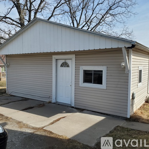 A small house with a white door and a window is available for rent.