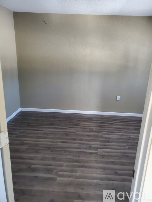 A room with wooden flooring and a wall.