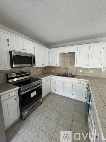 A kitchen with white cabinets and a tile floor.