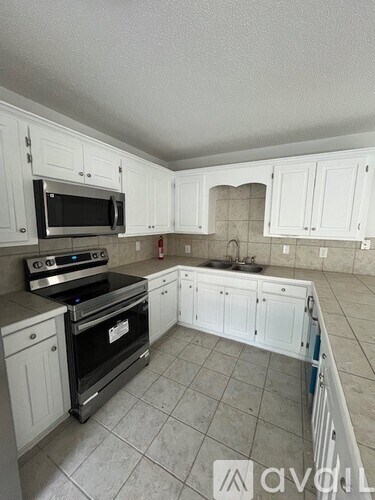 A kitchen with white cabinets and a tile floor.
