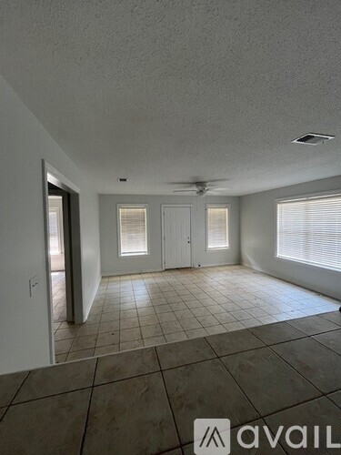 A spacious room with tile flooring and a ceiling fan.