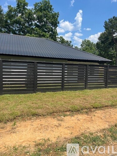 A black building with a metal roof and wooden shutters.