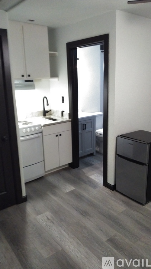 A kitchen with white cabinets and a black fridge.