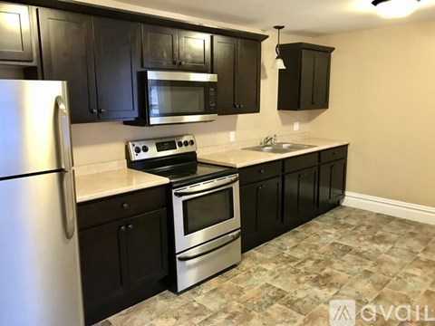 A kitchen with black cabinets and a stainless steel refrigerator.