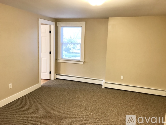 A room with a carpeted floor, a door, and a window.