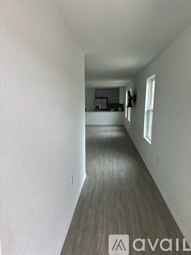 A long hallway with wood floors and white walls.